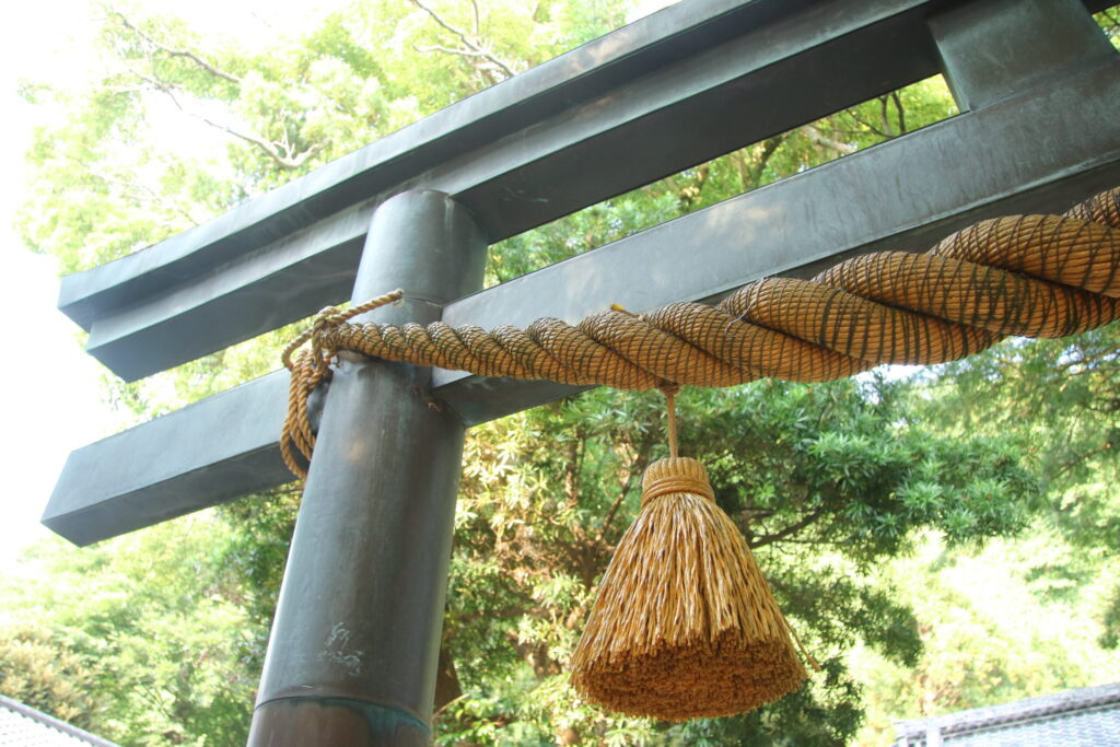 Close-up of a Shinto torii gate with sacred shimenawa rope and tassel, expressing quiet beauty and spiritual devotion in Japanese shrine culture