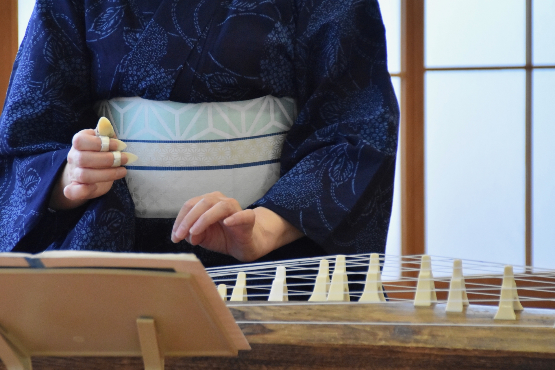 Woman in a kimono playing a traditional Japanese koto