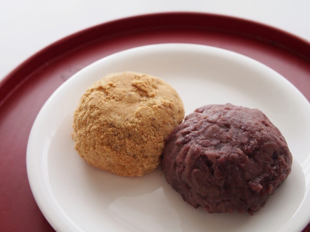 Two ohagi rice cakes coated with kinako and sweet red bean paste